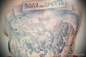 Фото тату на груди с изображением казаков верхом на лошадях и надписями на украинском языке. Детализированный рисунок в серо-черных тонах.