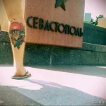 Фото тату сердца с украинским тризубом на ноге. Яркий рисунок татуировки в стиле традиционной татуировки с использованием синих и желтых цветов.