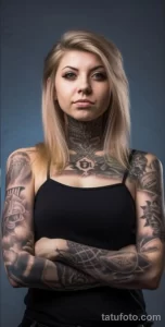 Фотография молодой женщины с уверенным взглядом и детализированными татуировками, покрывающими ее шею, руки и плечи.