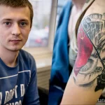 Фото тату на руке, изображающее сцену взятия Берлина советскими войсками в 1945 году. Детализированный рисунок татуировки с использованием черно-белой и красной гаммы.