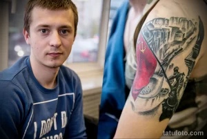 Фото тату на руке, изображающее сцену взятия Берлина советскими войсками в 1945 году. Детализированный рисунок татуировки с использованием черно-белой и красной гаммы.