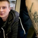 Фото тату на руке, изображающее знаменитый плакат "Родина-мать зовет!". Детализированный рисунок татуировки с использованием черно-белой гаммы и реалистичной проработкой деталей.