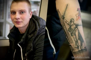 Фото тату на руке, изображающее знаменитый плакат "Родина-мать зовет!". Детализированный рисунок татуировки с использованием черно-белой гаммы и реалистичной проработкой деталей.