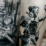 Фото татуировки на руке, изображающей сцены военных действий, портрет солдата и танк времен Великой Отечественной войны.
