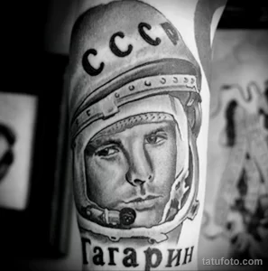 Фото тату: реалистичный черно-белый портрет Юрия Гагарина в скафандре на руке, с надписью "Гагарин".