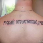 Фото тату: черная надпись на спине "Русский - это состояние души", выполненная простым шрифтом.