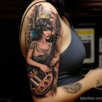 A woman with a sleeve tattoo of various musical symbols and instruments, playing a guitar in a music studio 4 - 07,11,2023 tatufoto.com