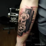 Close-up of a tattoo depicting a classic film reel and clapperboard on a forearm 1_2 16.11.2023 tatufoto.com 13