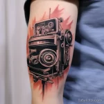 Detailed tattoo of a camera with a film strip from 'Cinema Paradiso' on a bicep 1_2 16.11.2023 tatufoto.com 23