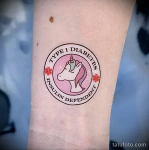 Фото тату единорога в круге с надписью 'Type 1 Diabetes Insulin Dependent'. Цветная татуировка в мультяшном стиле.