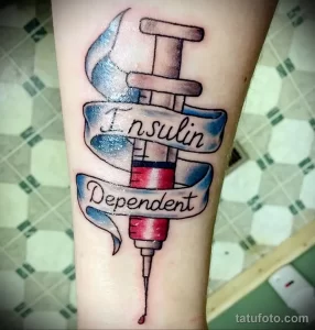 Фото тату шприца с надписью 'Insulin Dependent' на руке. Цветная татуировка в стиле олдскул.