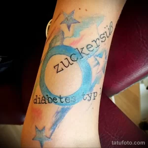 Фото татуировки на руке с надписью 'zuckersüß diabetes typ' и изображением голубой капли. Необычный рисунок татуировки на немецком языке.