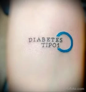 Фото минималистичной татуировки на руке с надписью "DIABETES TIPO1" и небольшим синим кругом. Простой и лаконичный дизайн, выполненный тонкими линиями.