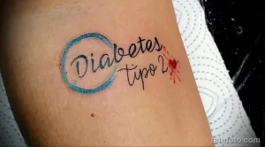 Цветное фото татуировки на руке с надписью "Diabetes tipo 2" и изображением капелек крови. Простой и символичный рисунок.