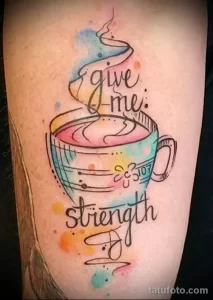Фото акварельной татуировки на руке с изображением чашки кофе и надписи "give me strength". Яркий и красочный рисунок, выполненный в технике акварели.