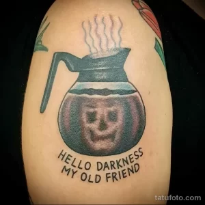 Фото тату на плече: кофейник с черепом внутри и надписью 'Hello Darkness My Old Friend'.