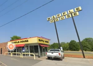 Фото: вывеска ресторана 'Waffle House' на фоне голубого неба. Видны яркие неоновые буквы и логотип ресторана.