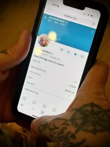 Фотография смартфона с открытой страницей OnlyFans, на руках владельца видны татуировки. Изображение демонстрирует связь между тату и современными цифровыми платформами.