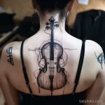 Фотография элегантной татуировки виолончели на спине девушки, выполненной в черно-белой гамме с использованием тонких линий и геометрических фигур.