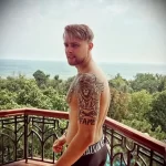 Фотография мужчины с татуировкой льва на плече и спине, демонстрирующая детализированный рисунок татуировки.