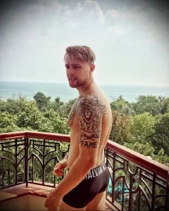 Фотография мужчины с татуировкой льва на плече и спине, демонстрирующая детализированный рисунок татуировки.