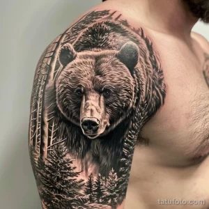 Фото тату медведя на плече в стиле реализм. Детализированный рисунок с изображением морды медведя и леса на фоне.