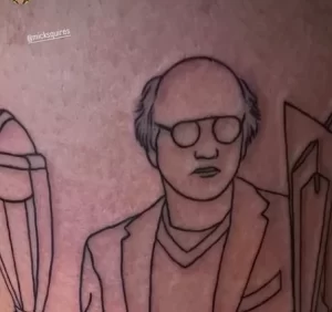 Черно-белая татуировка в стиле лайнарт с портретом Ларри Дэвида из Curb Your Enthusiasm. Четкие линии и минималистичный дизайн.