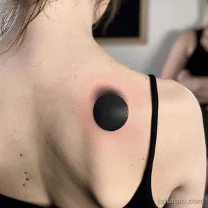 Фото тату в стиле Blackwork на спине, изображающее черный круг с растушевкой, создающий эффект затмения.