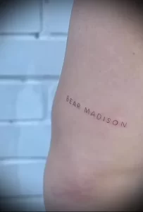 Фото тату с надписью 'BEAR MADISON' на внутренней стороне предплечья. Тонкие линии, минималистичный стиль, нежная татуировка.