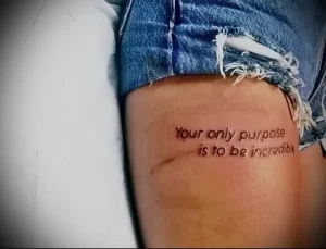 Фото минималистичной татуировки надписью 'Your only purpose is to be incredible' на бедре девушки. Идеально для поиска идей.