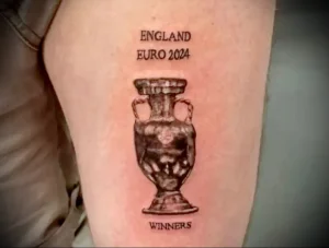 Фотография татуировки на руке, изображающей кубок Евро 2024 с надписью "ENGLAND EURO 2024 WINNERS". Видна детализация рисунка и четкость линий.