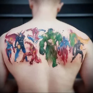 Фото акварельной татуировки с изображением супергероев Marvel и DC на спине мужчины. Яркие цвета и динамичные позы.