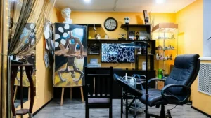 Фото интерьера тату-студии с картинами на стенах, удобным креслом и ярким освещением. Атмосфера творчества и индивидуальности.