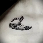 Черно-белое фото тату на коже с изображением предсказания в печенье 'Lucky'. Милый и забавный рисунок.