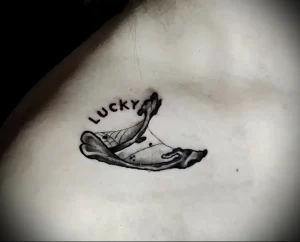 Черно-белое фото тату на коже с изображением предсказания в печенье 'Lucky'. Милый и забавный рисунок.