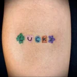 Фото тату: оригинальная татуировка надписи "LUCKY", выполненная в стиле патчворк с использованием разных цветов и текстур на руке.