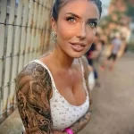 Фото тату на руке девушки, изображающее слона и розу. Татуировка выполнена в реалистичном стиле с высокой детализацией.