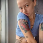 Фото тату: девушка с татуировками на руке в виде роз и павлина. Красивый и элегантный рисунок в ярких цветах.