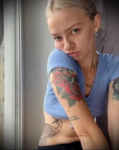 Фото тату: девушка с татуировками на руке в виде роз и павлина. Красивый и элегантный рисунок в ярких цветах.