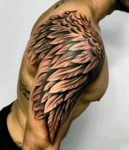 Фото тату: большое крыло на плече и верхней части руки, выполненное в реалистичном стиле с использованием градиентов и теней.