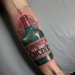 Фото тату бутылки с винтажной этикеткой и надписью "SHOWP V CHCOER" в стиле олдскул на предплечье. Яркий и красочный рисунок.