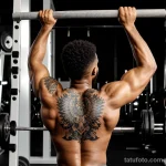 athletic man with a phoenix tattoo on his upper arm, symbolizing rebirth, lifting weights in a dark gym tattoo lion, on neck sex tatufoto.com 121