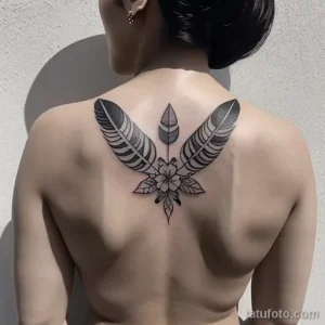 Фото тату на спине в стиле Blackwork с изображением венка из листьев и центрального цветка. Рисунок выполнен в черном цвете с использованием геометрических форм и узоров.