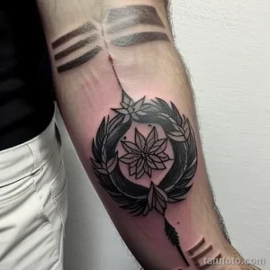 Фото тату на предплечье в стиле Blackwork с изображением венка из листьев и цветка. Рисунок выполнен в черном цвете с использованием геометрических форм и узоров.
