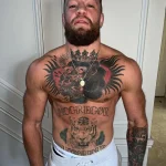 Фото тату Коннора Макгрегора: большая горилла с короной на груди, тигр на животе и надпись "MCGREGOR", выполненные в традиционном стиле.