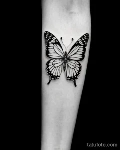 Черно-белое фото татуировки бабочки на предплечье. Детализированные крылья с тонкими линиями и узорами создают эффект легкости и воздушности.
