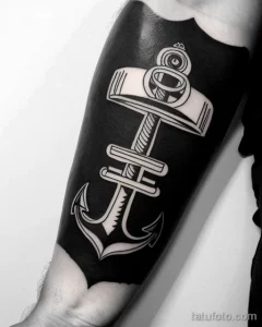 Черно-белое фото тату якоря в стиле Blackwork на руке. Контрастный рисунок с использованием только черного цвета.