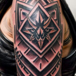 Фото тату: детализированная черно-серая татуировка на плече с изображением демонической головы, заключенной в геометрические фигуры. Подходит для поклонников мистических рисунков.