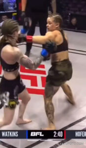 Фотография момента удара в бою MMA. На теле одной из спортсменок видны татуировки.