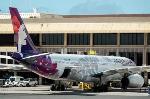 Фотография самолета Hawaiian Airlines, украшенного ярким дизайном с изображением гавайской богини и традиционными узорами. Видны детализированные рисунки на корпусе и хвосте.
